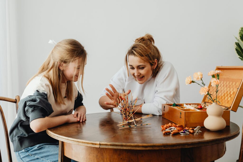 A mom and her teen daughter happily play a game together.